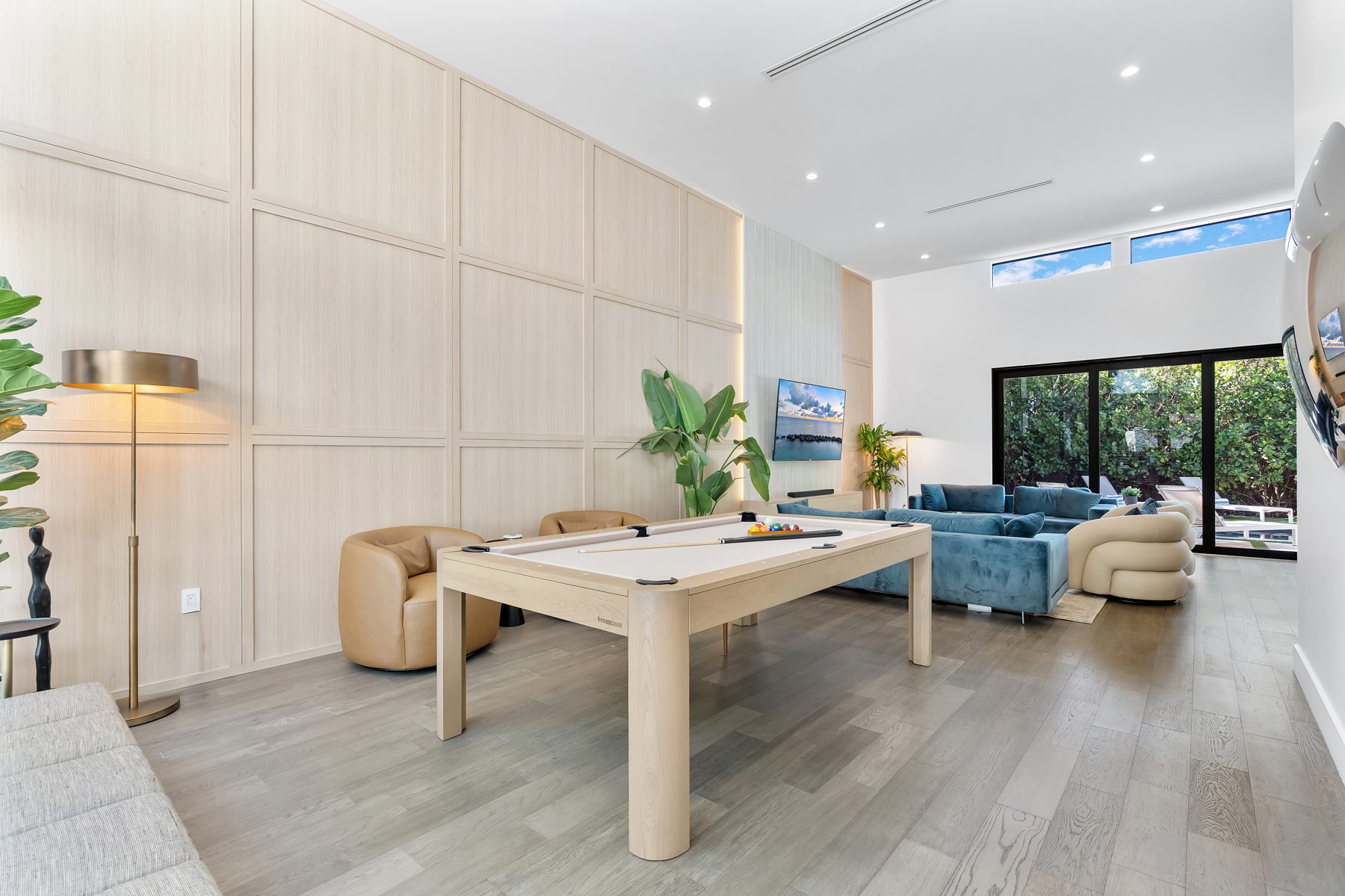 Living room with wood-panel wall and blue seating in a Los Angeles residence by Naomi Satya Interiors