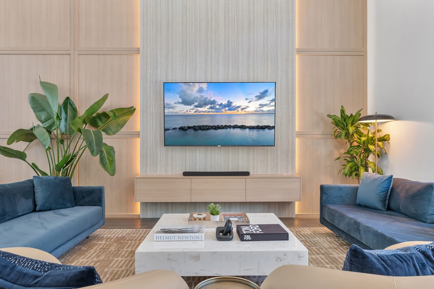 Living room with blue velvet sofas and ocean-view artwork in an Orange County home by Naomi Satya Interiors