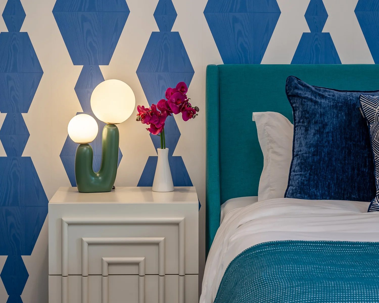 Bedroom with blue geometric wallpaper and teal headboard in a Palm Springs home by Naomi Satya Interiors