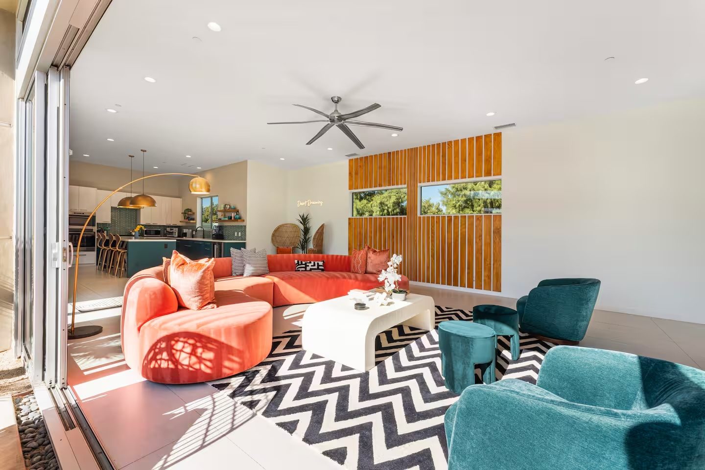 Indoor-outdoor living room with coral and teal furnishings in a Palm Springs home by Naomi Satya Interiors
