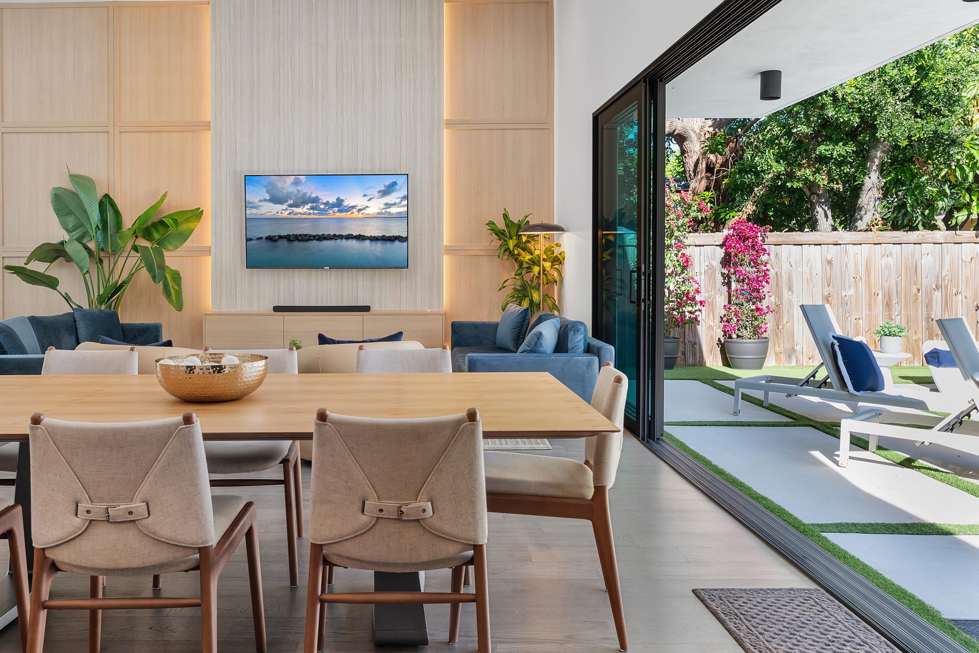 Open-plan living and dining room opening to a patio in a Miami home designed by Naomi Satya Interiors